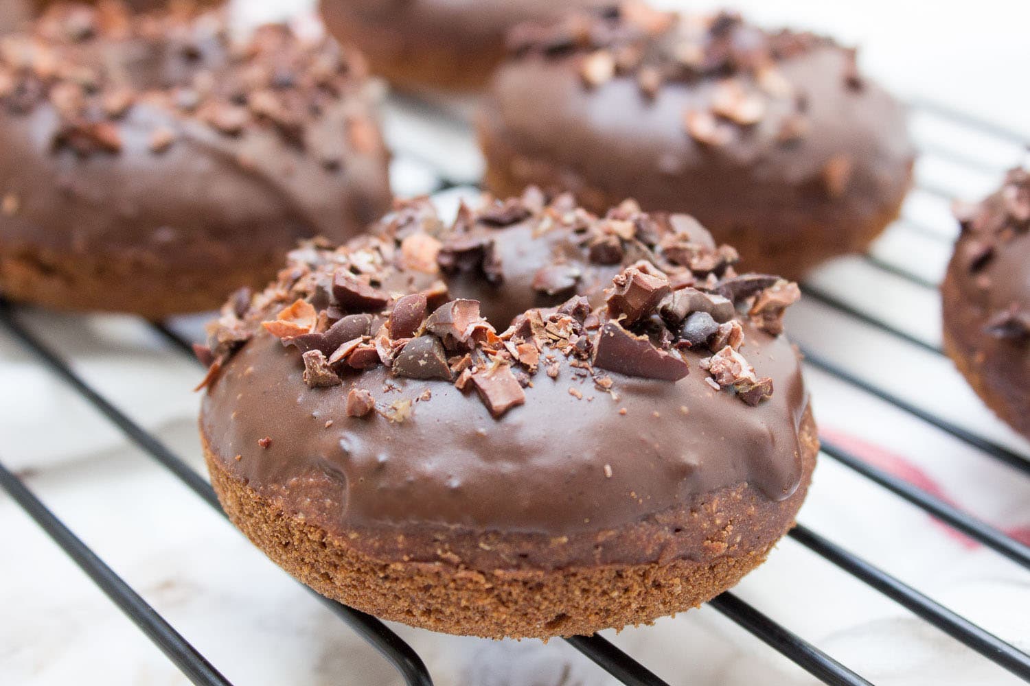 Baked whole wheat double chocolate banana donuts infused with cinnamon and topped with melted dark chocolate. These are made with all healthy ingredients, nutritious and contains no refined sugars! CLICK to read more or PIN for later! #donuts #doughnuts #healthy #easy