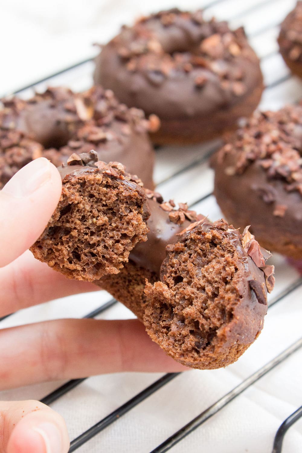 Baked whole wheat double chocolate banana donuts infused with cinnamon and topped with melted dark chocolate. These are made with all healthy ingredients, nutritious and contains no refined sugars! CLICK to read more or PIN for later! #donuts #doughnuts #healthy #easy