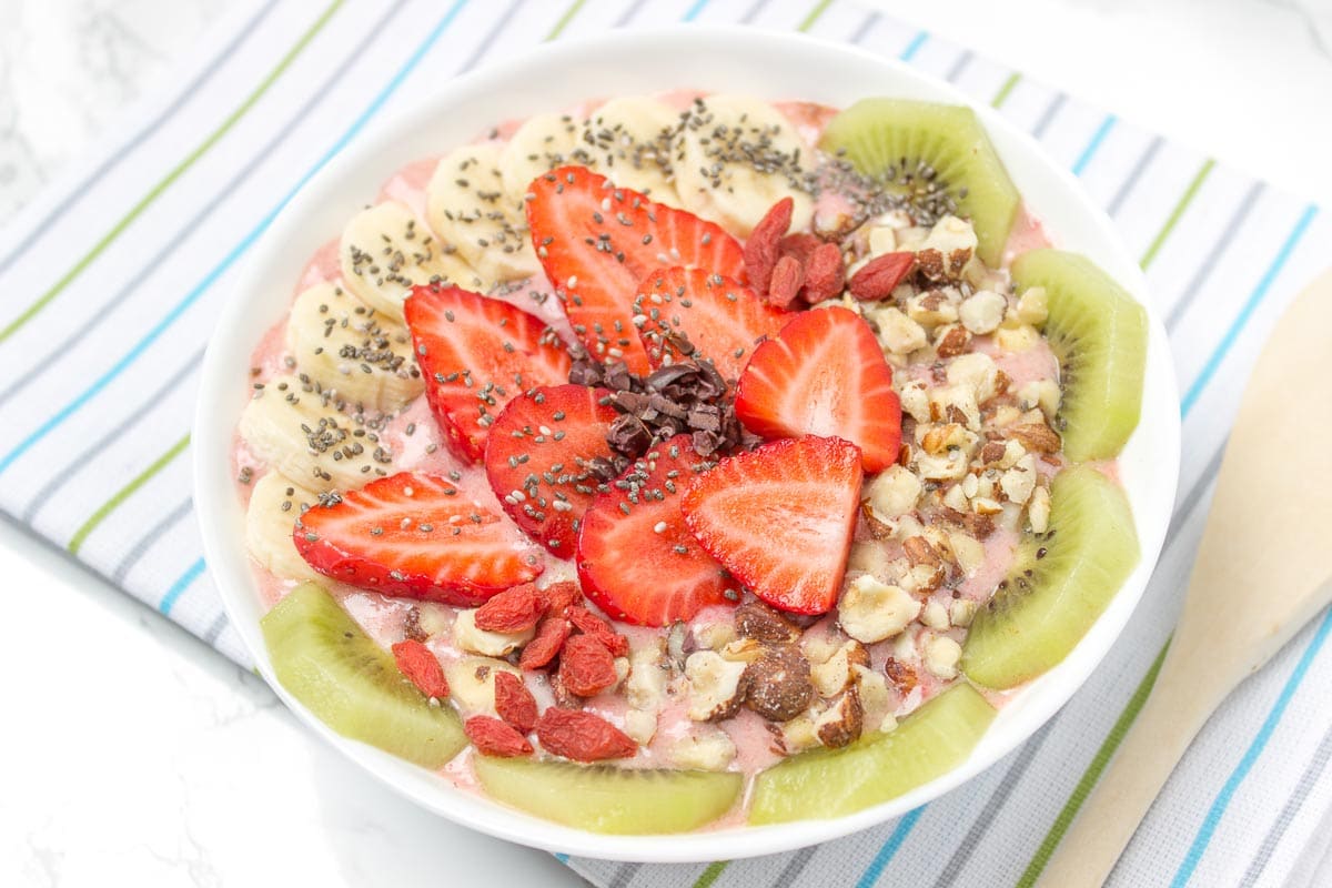 Creamy and sweet with a kick of spicy ginger, this immune boosting Strawberry Ginger Smoothie Bowl is a fresh and HEALTHY breakfast done in just minutes! Packed with nutrients, low calorie and WITHOUT added sugars. Vegan, gluten free and dairy free. DELICIOUS! #vegan #glutenfree #dairyfree #sugarfree #healthy #smoothie #recipe #breakfast #kids