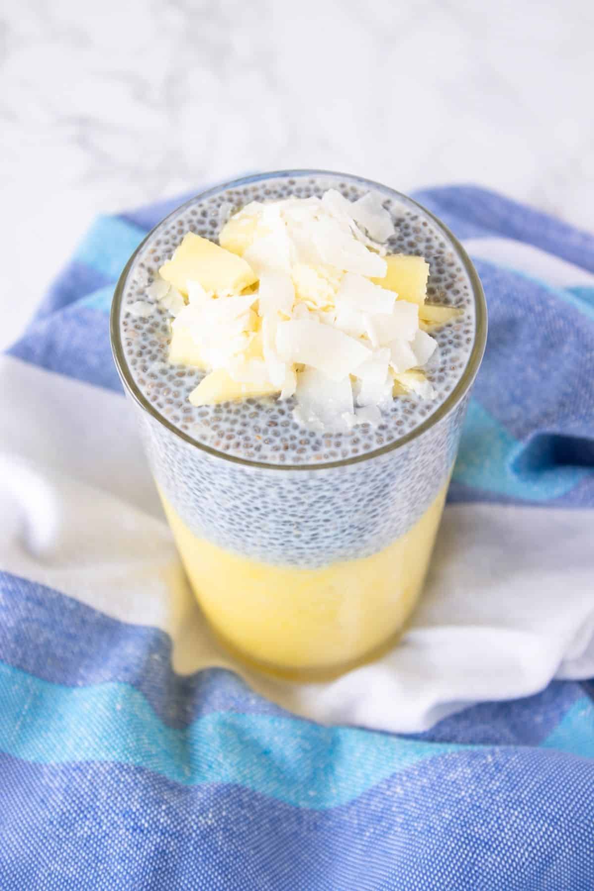 Pineapple coconut chia pudding layered with pineapple puree and topped with fresh pineapple and coconut flakes