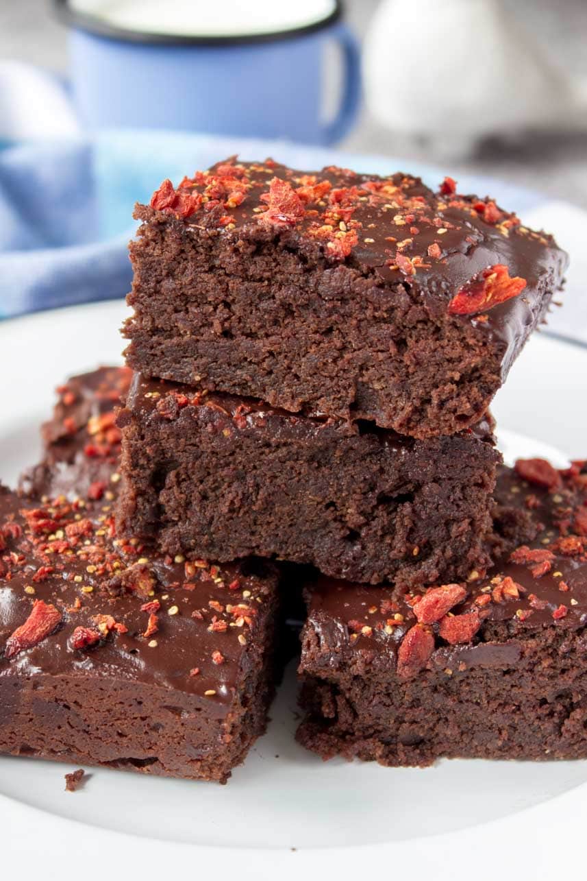 Healthy fudgy dark Chocolate Maca Tahini Brownies with melted chocolate glaze topped with chopped goji berries