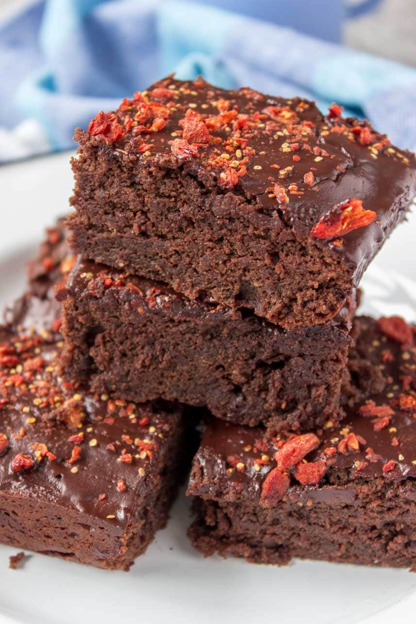 Healthy fudgy dark Chocolate Maca Tahini Brownies with melted chocolate glaze topped with chopped goji berries