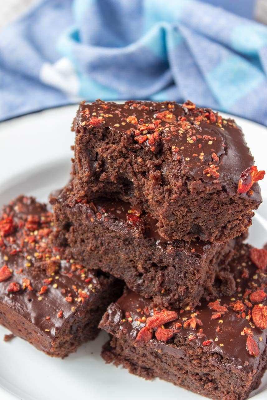 Healthy fudgy dark Chocolate Maca Tahini Brownies with melted chocolate glaze topped with chopped goji berries