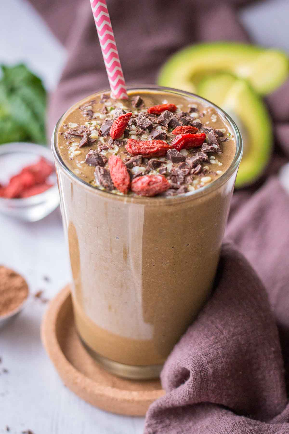 Chocolate Avocado Smoothie served in a smoothie glass topped with goji berries and chocolate