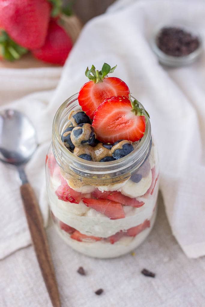 strawberry oatmeal with yogurt topped with banana and almond butter