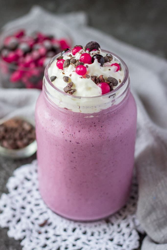 Mixed berry smoothie with almond milk topped with cream and fresh fruits