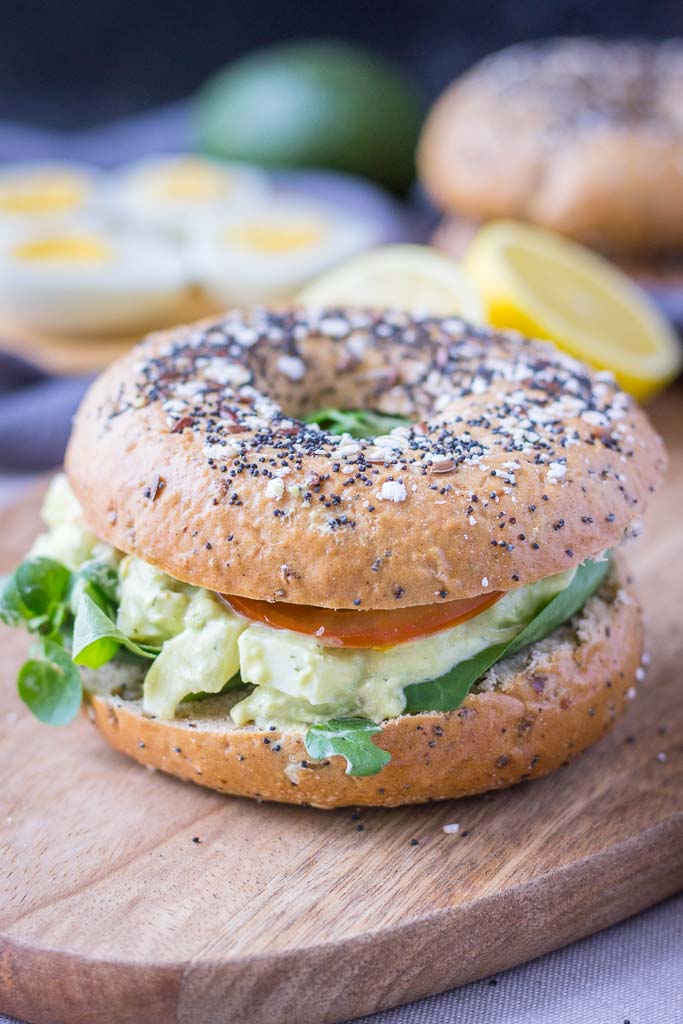 Healthy mayo-free Avocado Egg Salad served with fresh veggies in a whole-grain bagel