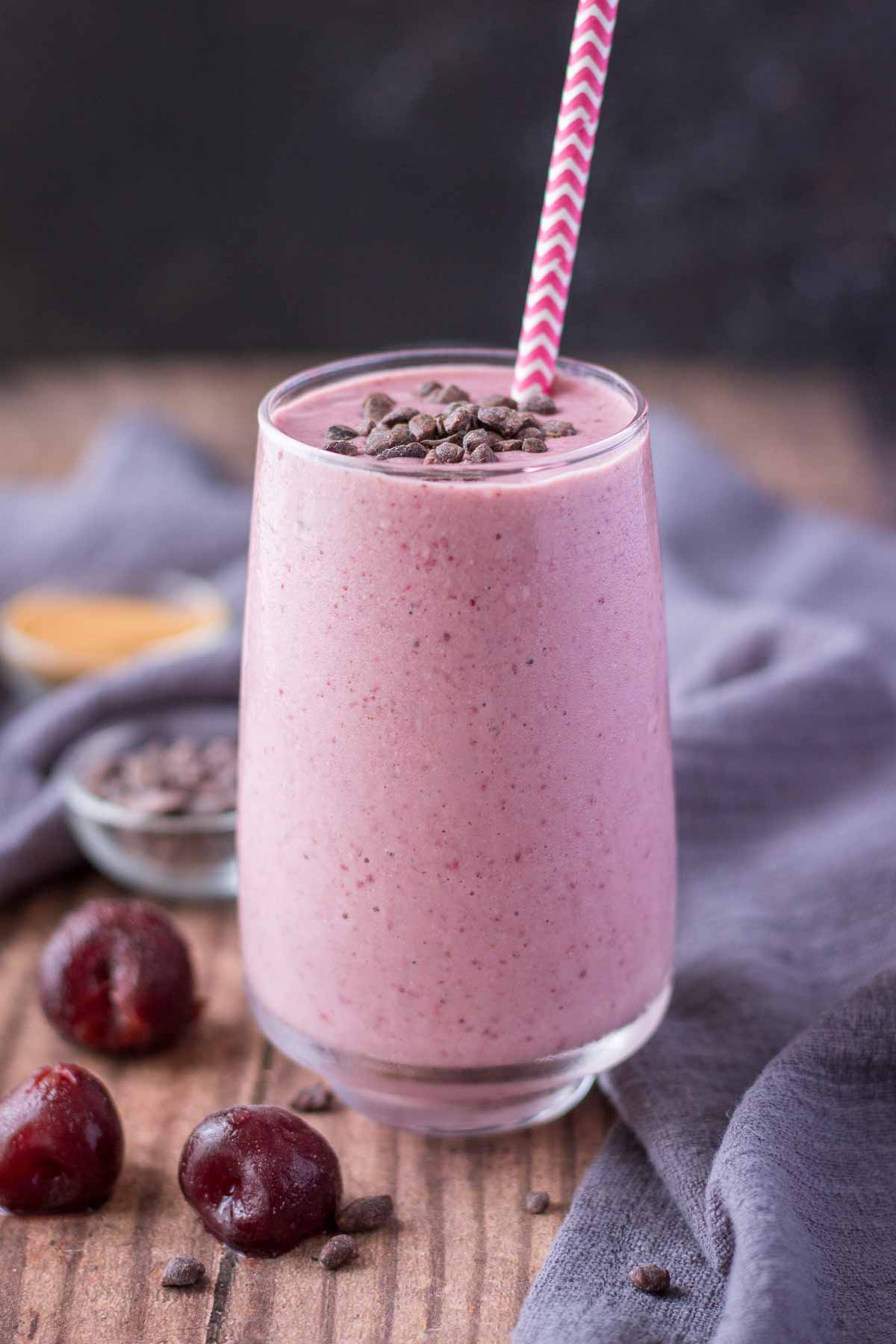 Cherry Banana Smoothie served in a glass with a straw topped with chocolate