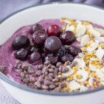 Blueberry Avocado Smoothie served in a bowl topped with blueberries almonds and chocolate