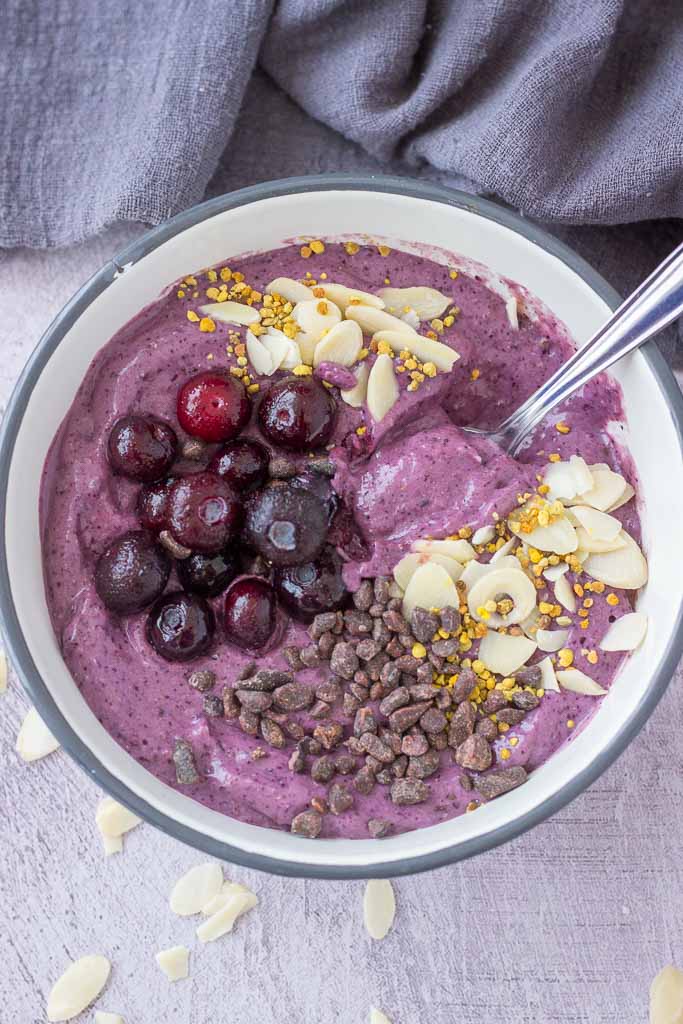 Blueberry Avocado Smoothie served in a bowl topped with blueberries almonds and chocolate