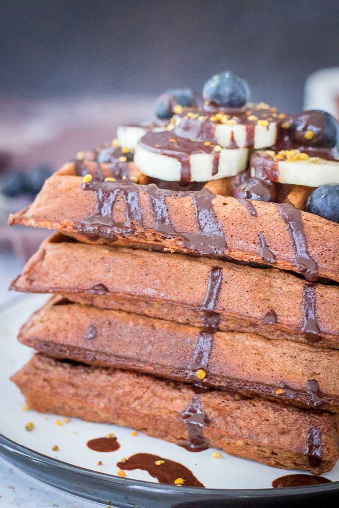 Chocolate Banana Waffles made with oats topped with chocolate syrup and fresh fruits