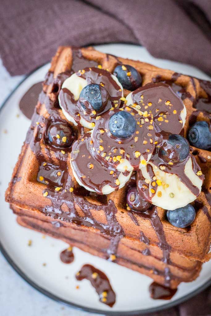 Healthy Chocolate Banana Waffles topped with chocolate syrup and fresh fruits