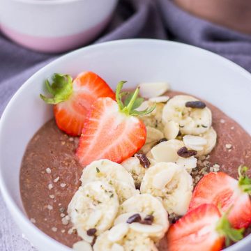 Healthy chocolate oatmeal porridge topped with banana and fresh strawberries