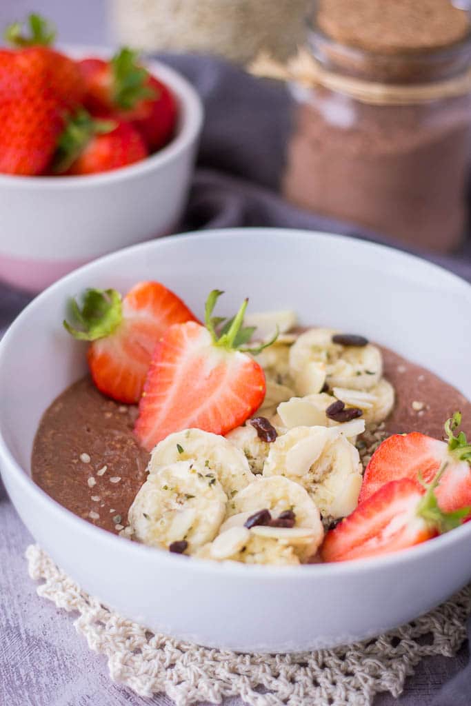 Chocolate oatmeal breakfast bowl served with fresh strawberries and banana