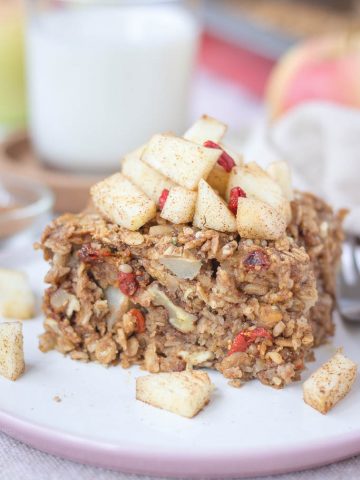 Slice of apple cinnamon baked oatmeal topped with slices of fresh apples served on a plate