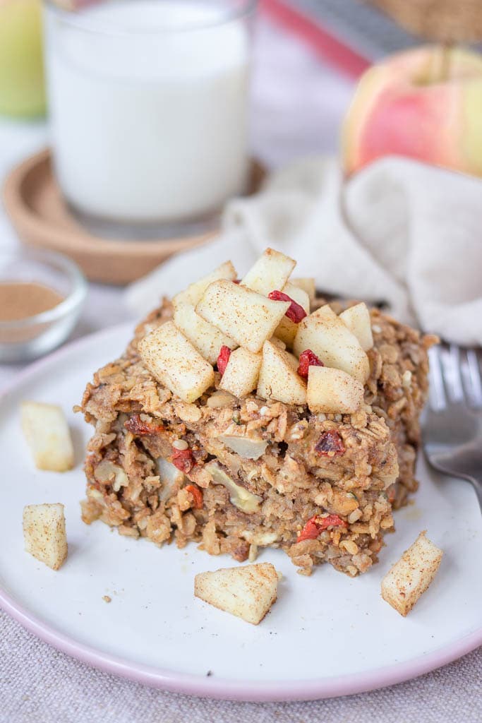 Slice of apple cinnamon baked oatmeal topped with slices of fresh apples served on a plate