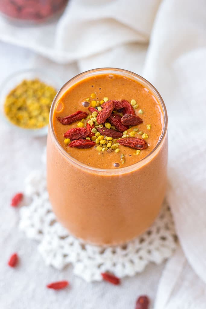 Goji Berry Smoothie served in a tall glass topped with goji berries and bee pollen
