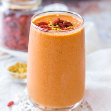 Goji Berry Smoothie served in a tall glass topped with goji berries and bee pollen