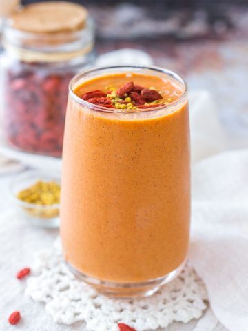 Goji Berry Smoothie served in a tall glass topped with goji berries and bee pollen