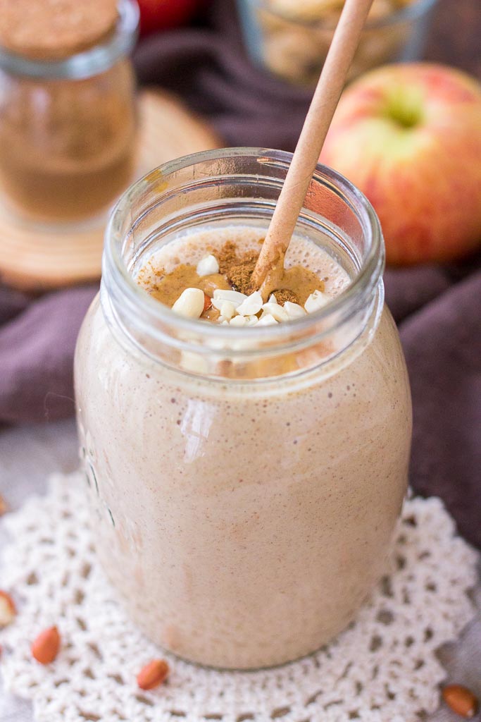 Apple Peanut Butter Smoothie served with a straw in a glass jar topped with creamy peanut butter and crushed peanuts