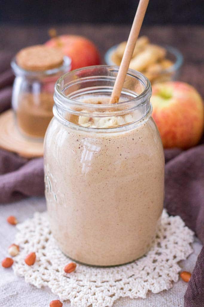 Apple Peanut Butter Smoothie served with a straw in a glass jar topped with creamy peanut butter and crushed peanuts