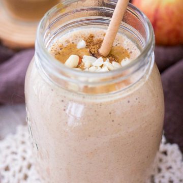 Apple Peanut Butter Smoothie served with a straw in a glass jar topped with creamy peanut butter and crushed peanuts