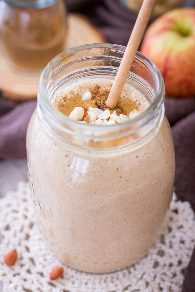 Apple Peanut Butter Smoothie served with a straw in a glass jar topped with creamy peanut butter and crushed peanuts