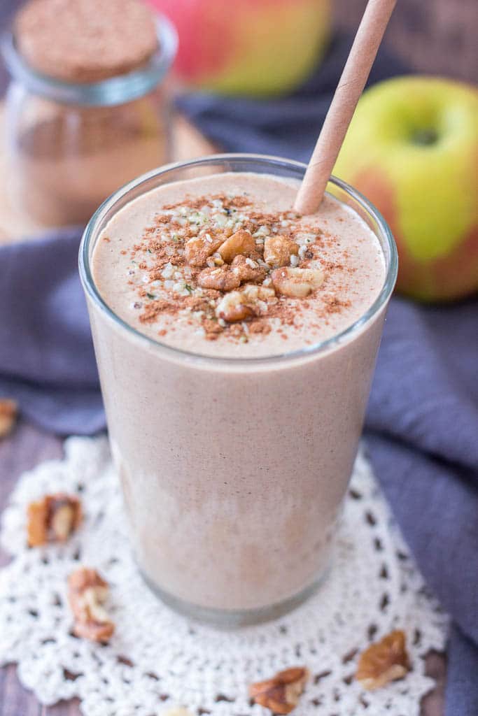 Healthy Apple Pie Smoothie topped with walnuts cinnamon and hemp seeds served in a glass with a straw