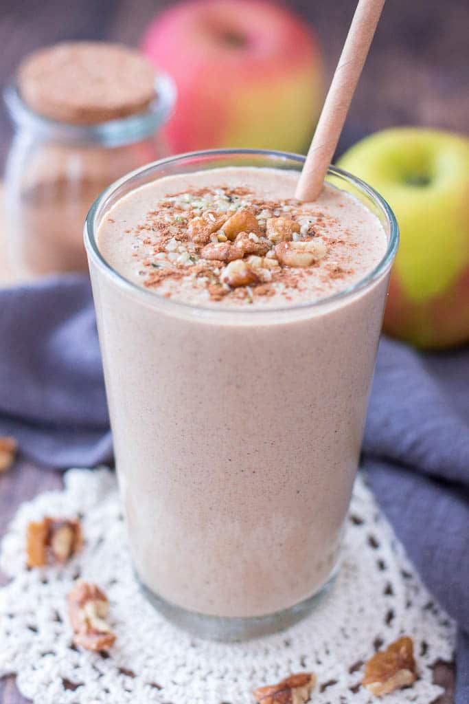 Apple Pie Smoothie topped with walnuts cinnamon and hemp seeds served in a glass with a straw