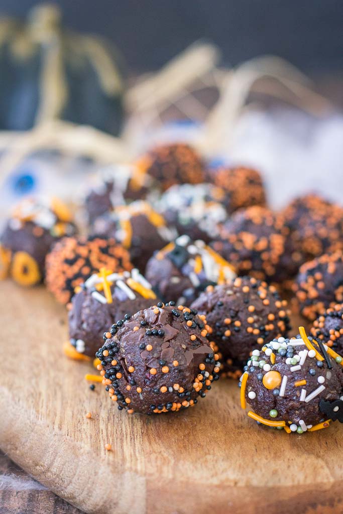 Halloween Brownie Bites made with dark chocolate rolled in Halloween sugar sprinkles served on a wooden plate