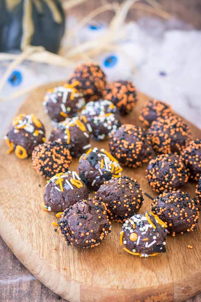 Halloween Brownie Bites made with dark chocolate rolled in Halloween sugar sprinkles served on a wooden plate