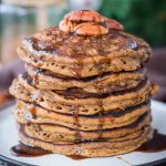 Gingerbread Pancakes topped with pecans and drizzled with maple syrup served on a plate