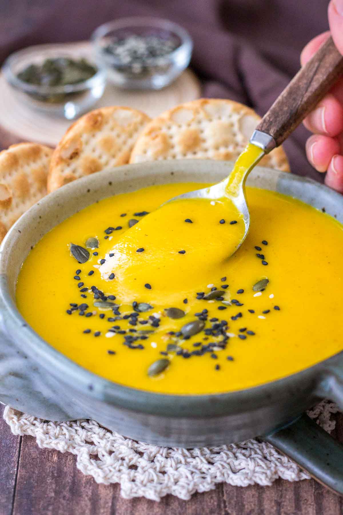 Creamy Carrot Soup served in a bowl with crackers topped with seeds