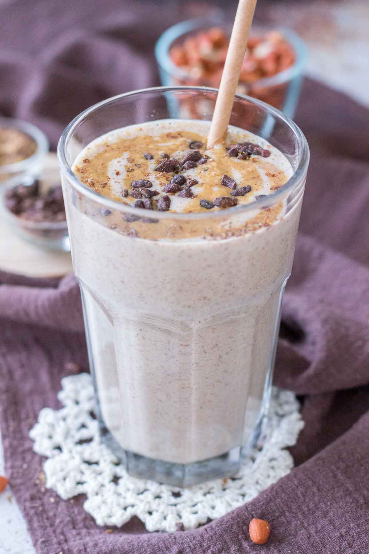 Peanut Butter Protein Shake topped with peanut butter and chocolate served in a glass with a straw