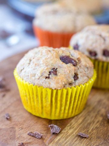 Banana chocolate chip muffins served on a wooden plate.