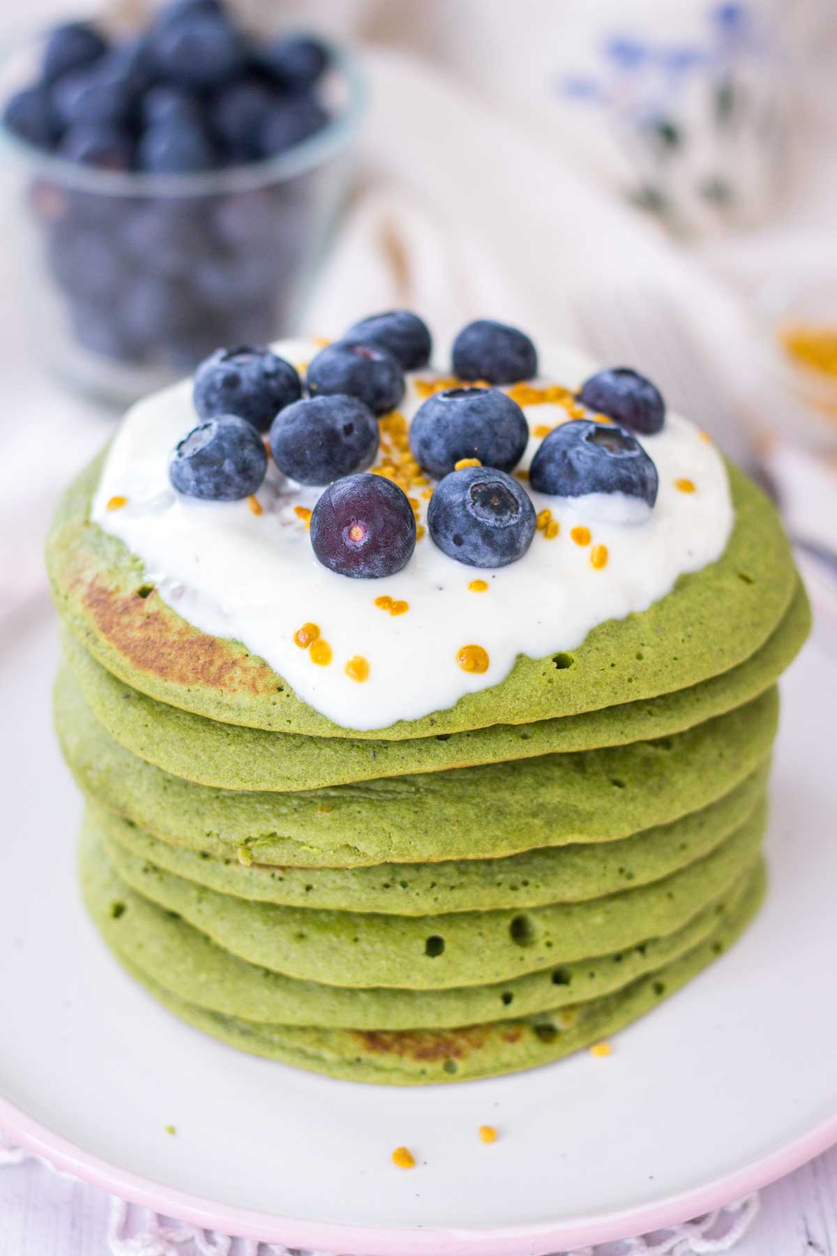 Matcha green tea pancakes served on a plate topped with fruits.