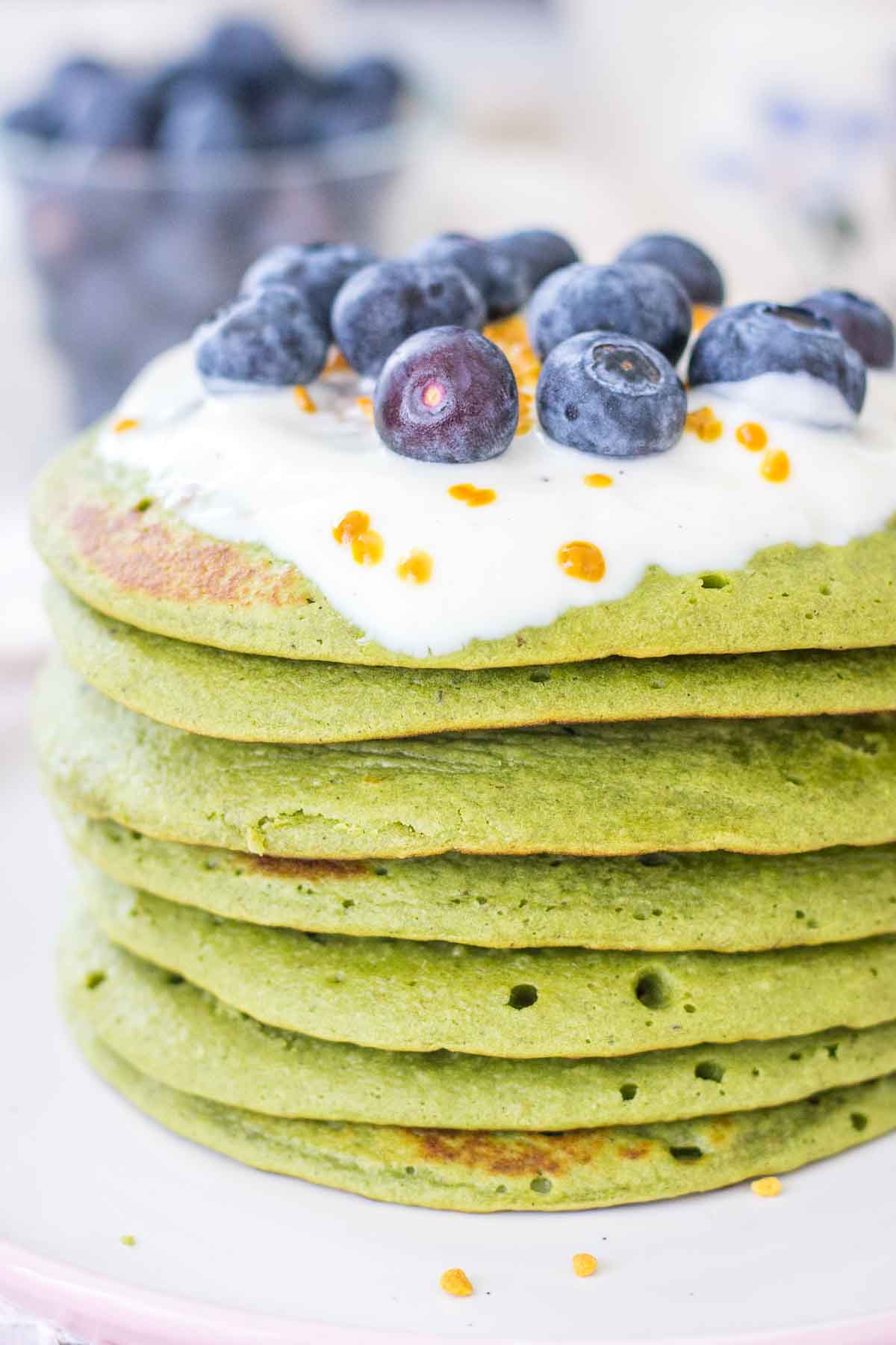Matcha green tea pancakes served on a plate topped with fruits.