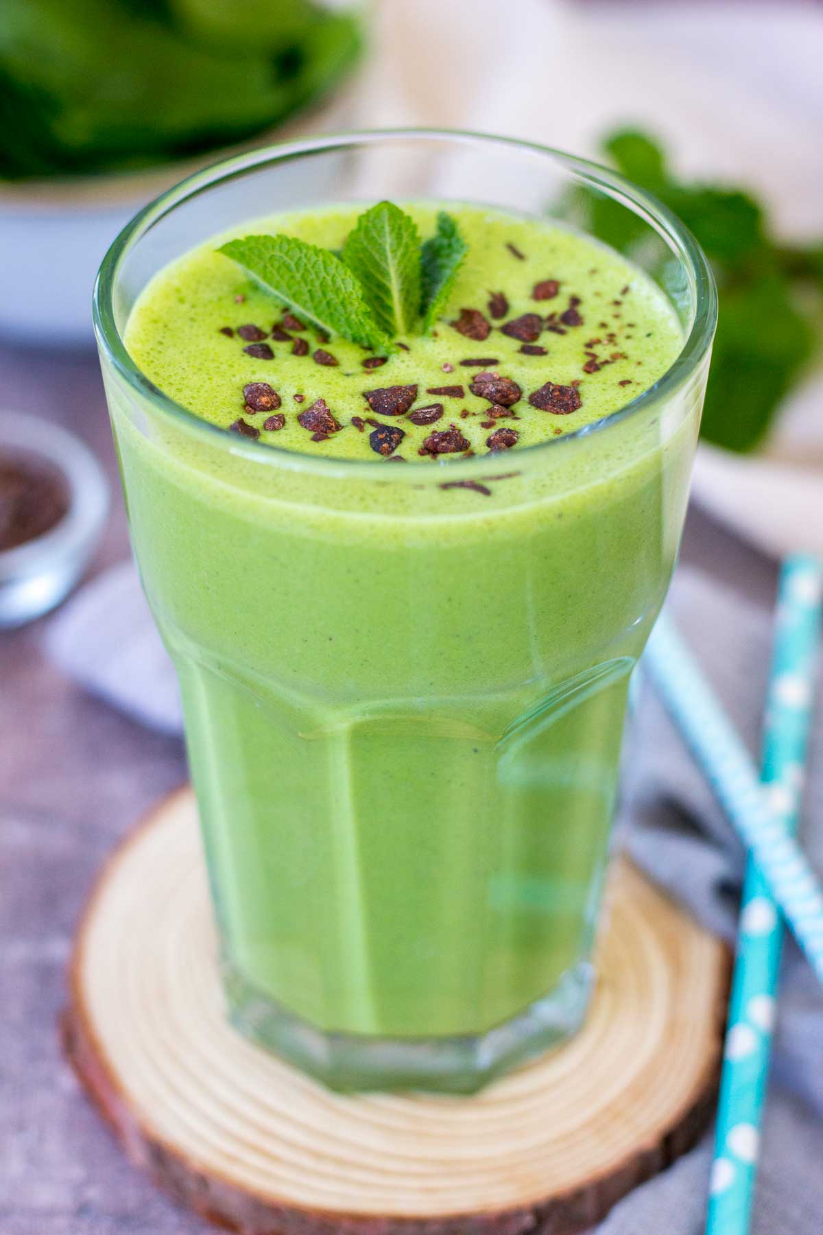 Shamrock protein shake served in a glass on a wooden coaster.