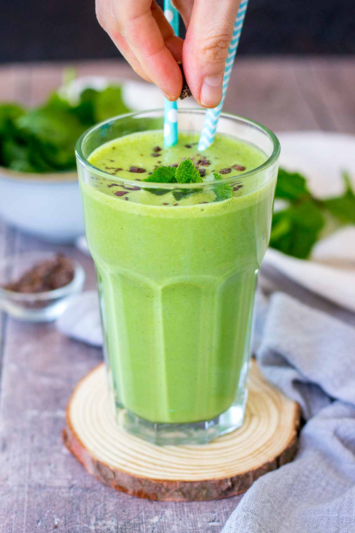 Shamrock protein shake served in a glass on a wooden coaster.