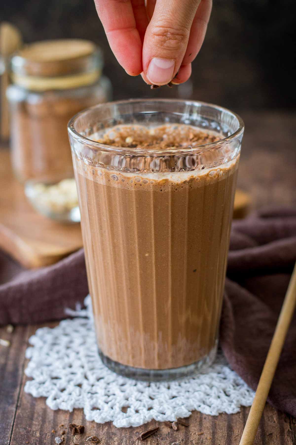 Hand adding chocolate to coffee smoothie