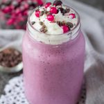Mixed Berry Smoothie topped with cream served in a glass with a straw