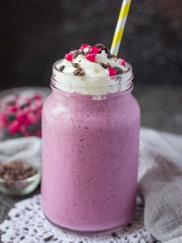 Berry Smoothie topped with cream served in a glass with a straw