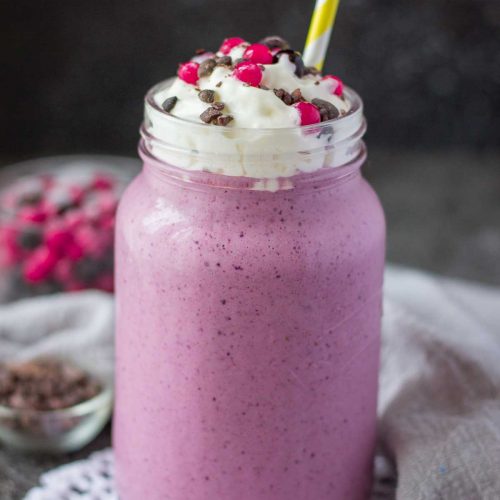 Berry Smoothie topped with cream served in a glass with a straw