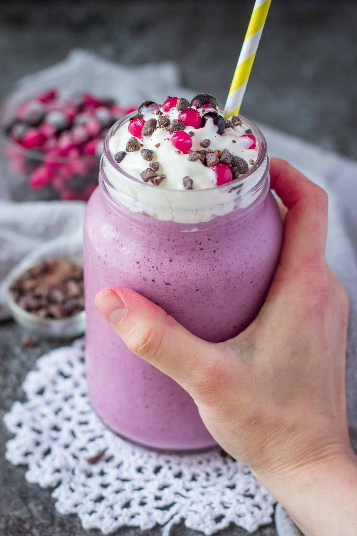 Hand holding a glass full of frozen berry smoothie