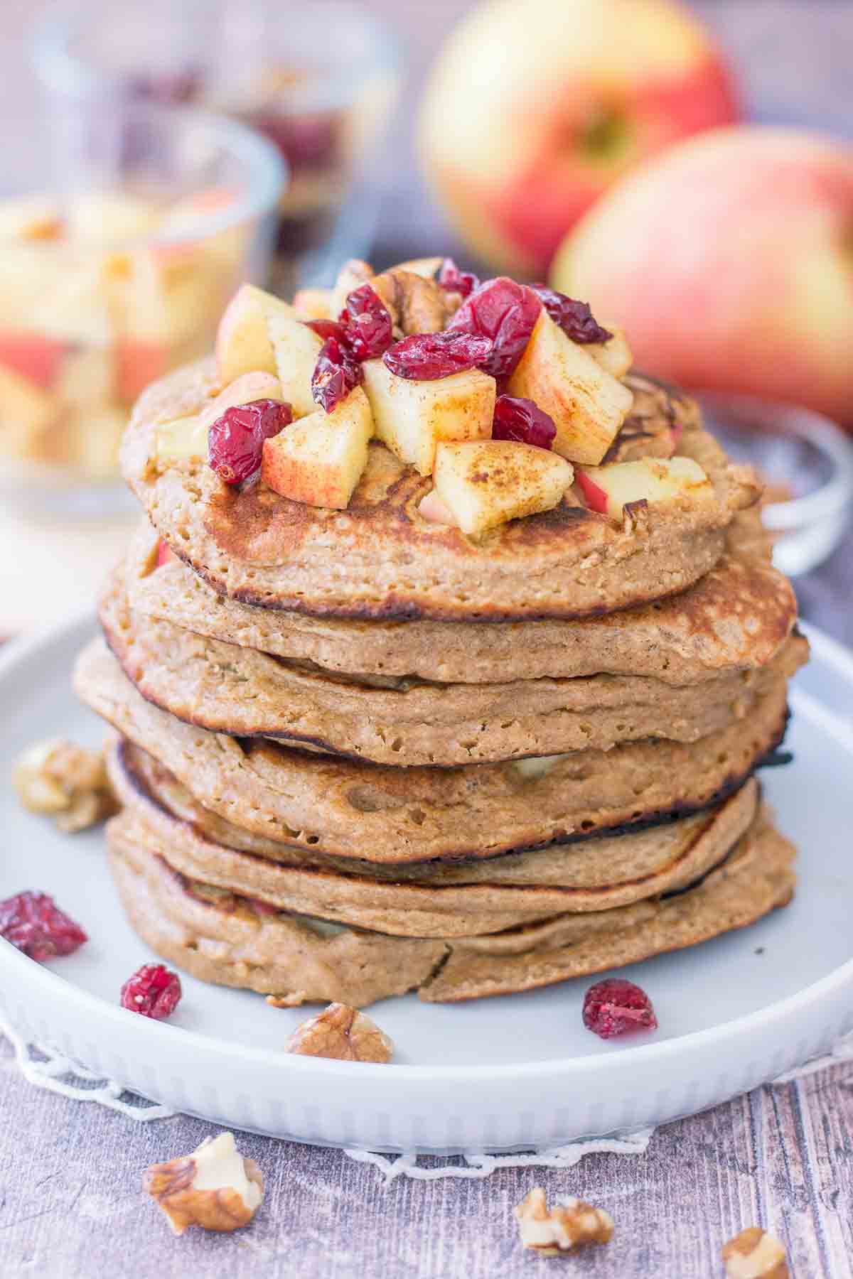 Apple Oatmeal Pancakes stacked on a plate topped with diced apples and cranberries