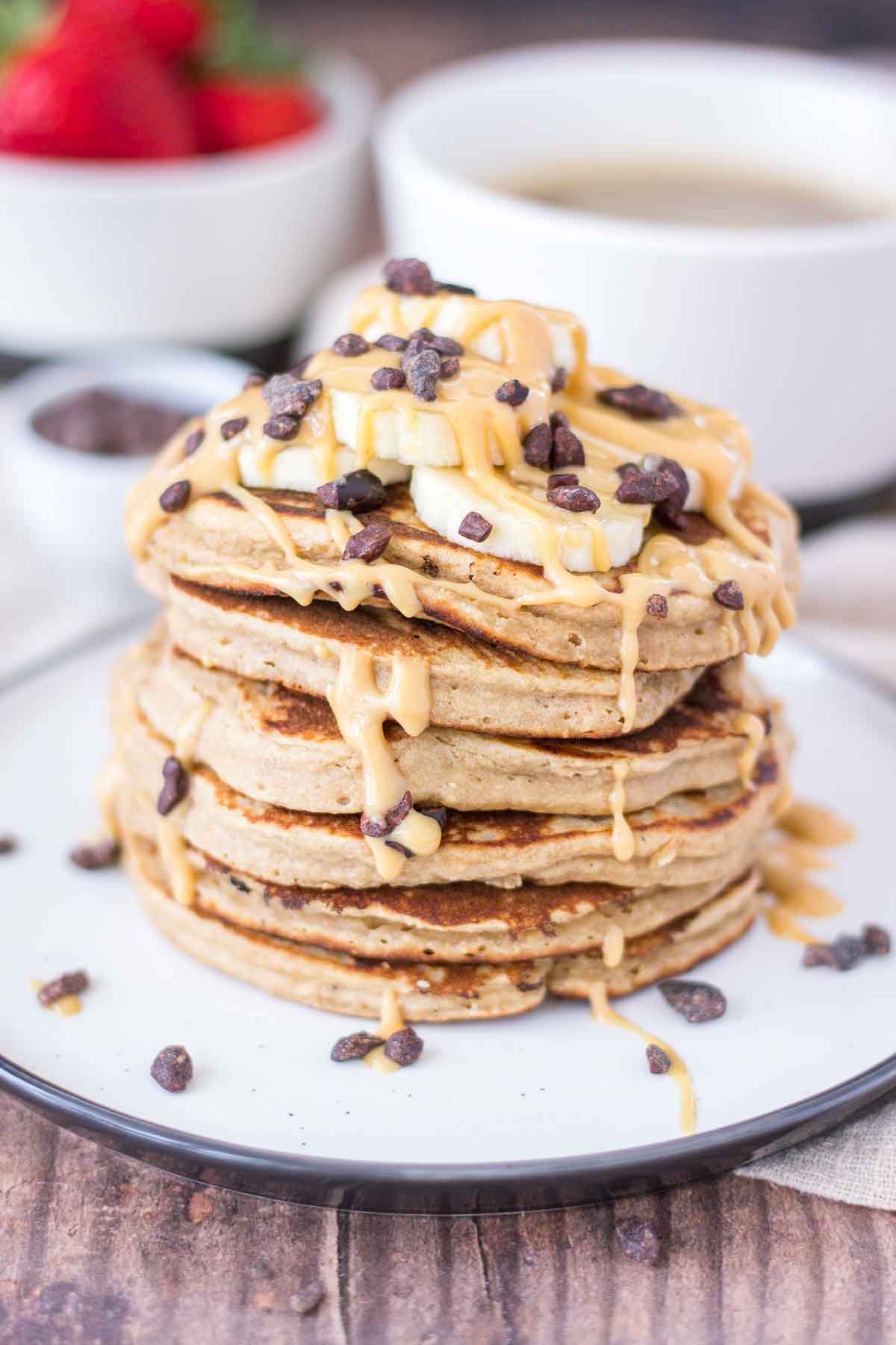 Peanut Butter Oatmeal Pancakes stacked on a plate topped with slices of banana and chocolate