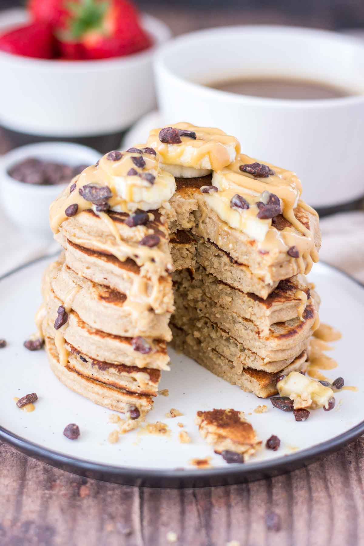 Peanut Butter Oatmeal Pancakes stacked on a plate topped with slices of banana and chocolate