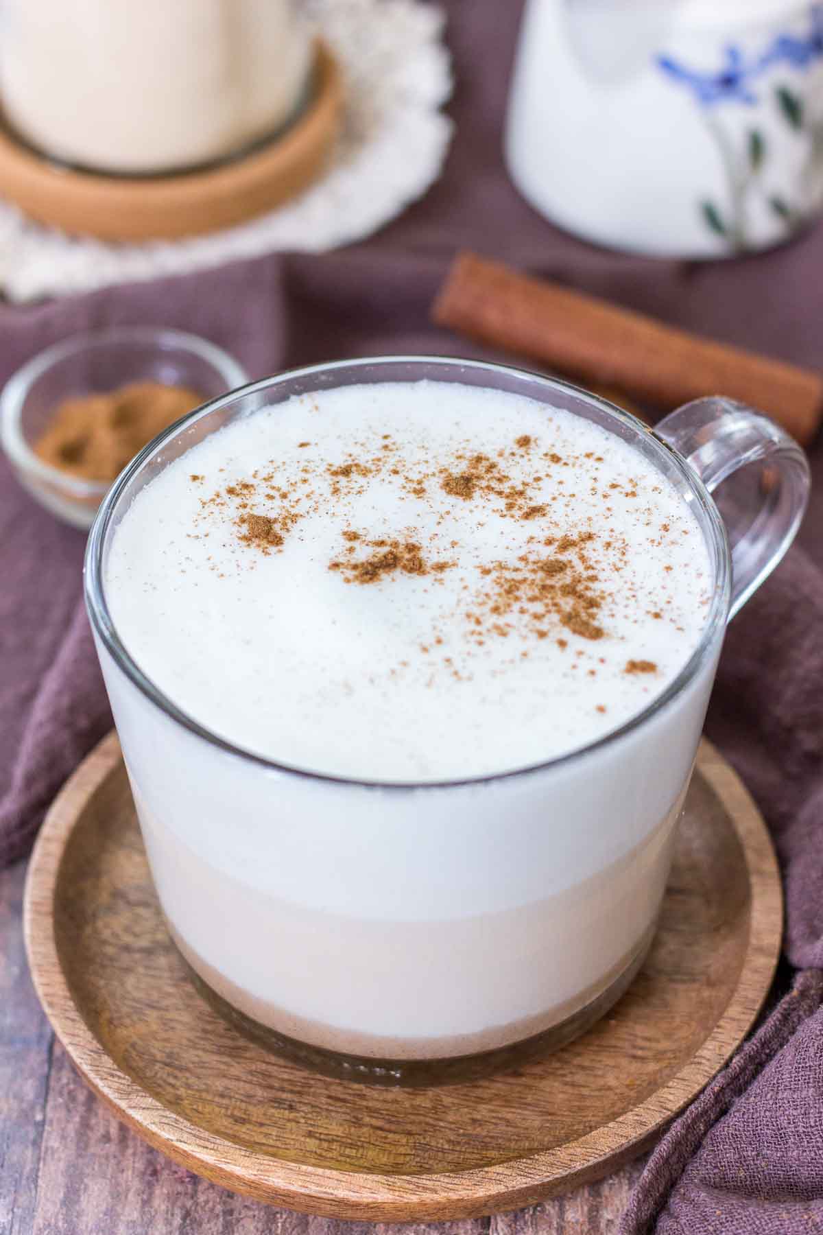 Maca Latte served in a clear mug topped with milk foam and cinnamon