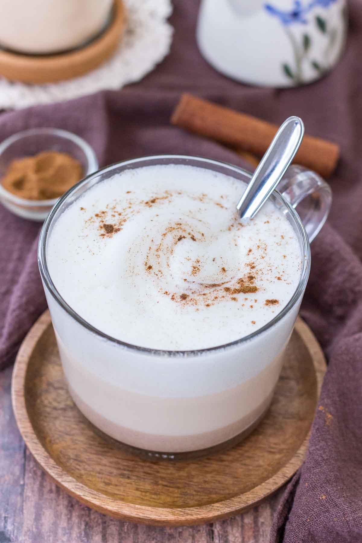Maca Latte served in a clear mug topped with milk foam and cinnamon