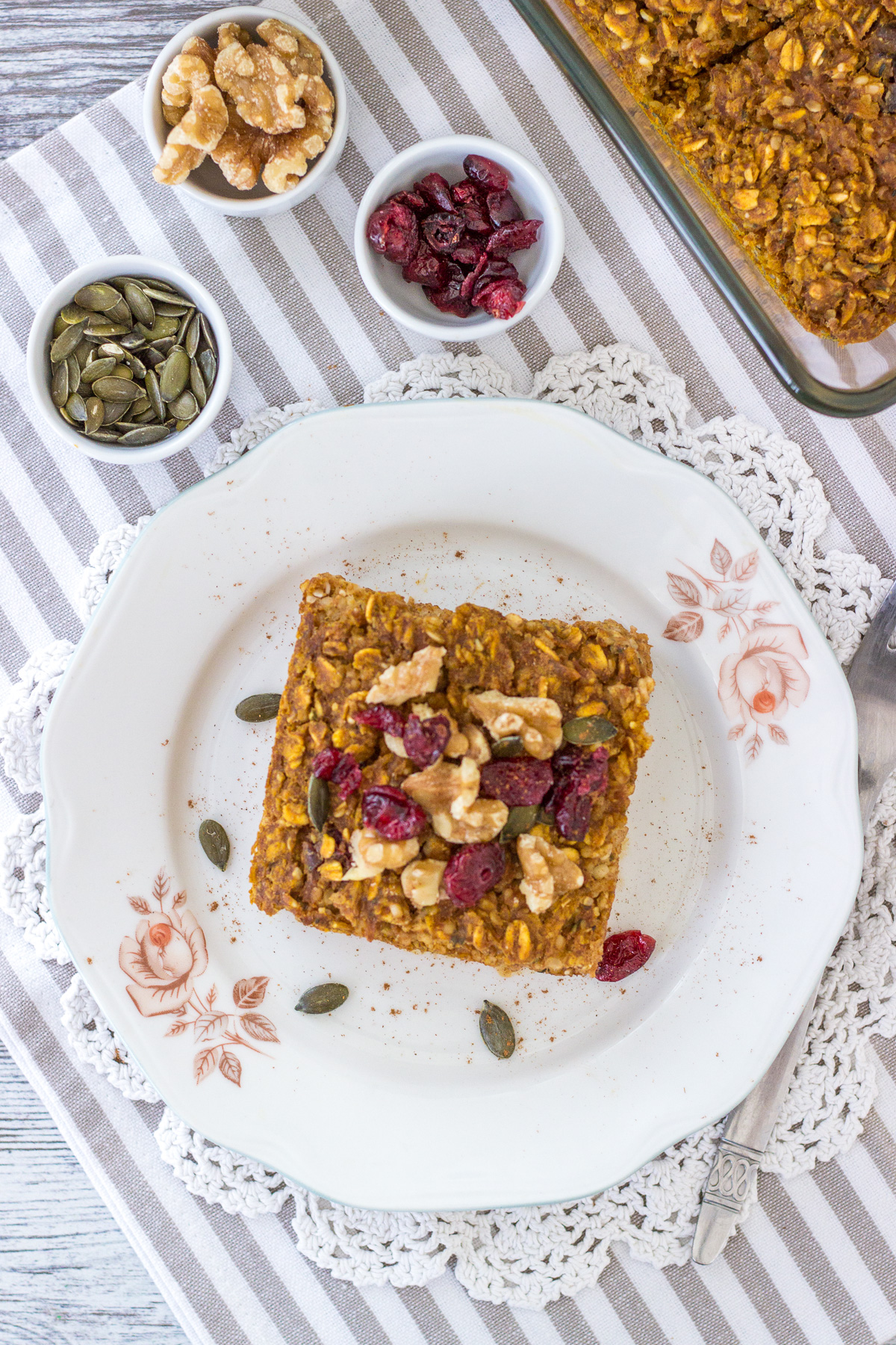 Pumpkin Baked Oatmeal on a plate topped with walnuts and cranberries